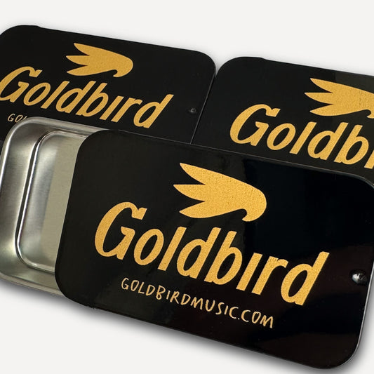 Black and gold Goldbird pick tins on a white background